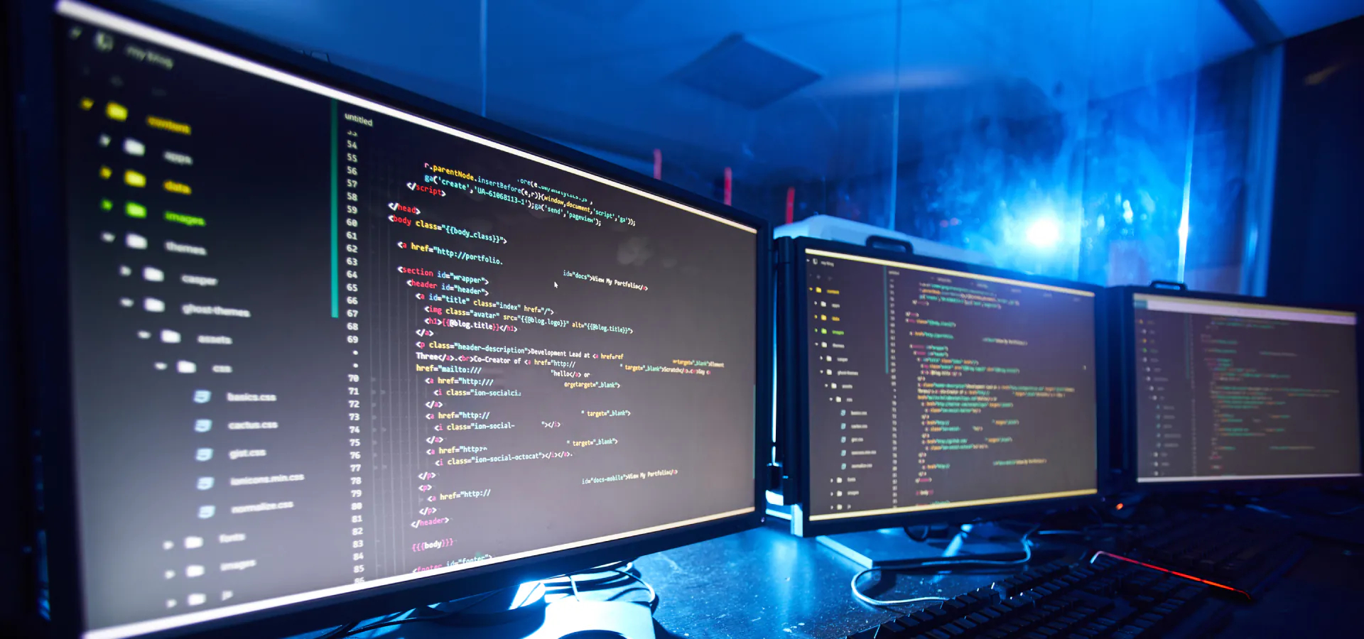 Top Web Application Testing Consulting Company: multiple monitors showing code in a blue-lit workspace